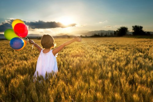 Enfant heureux avec des ballons dans un champs de blé..